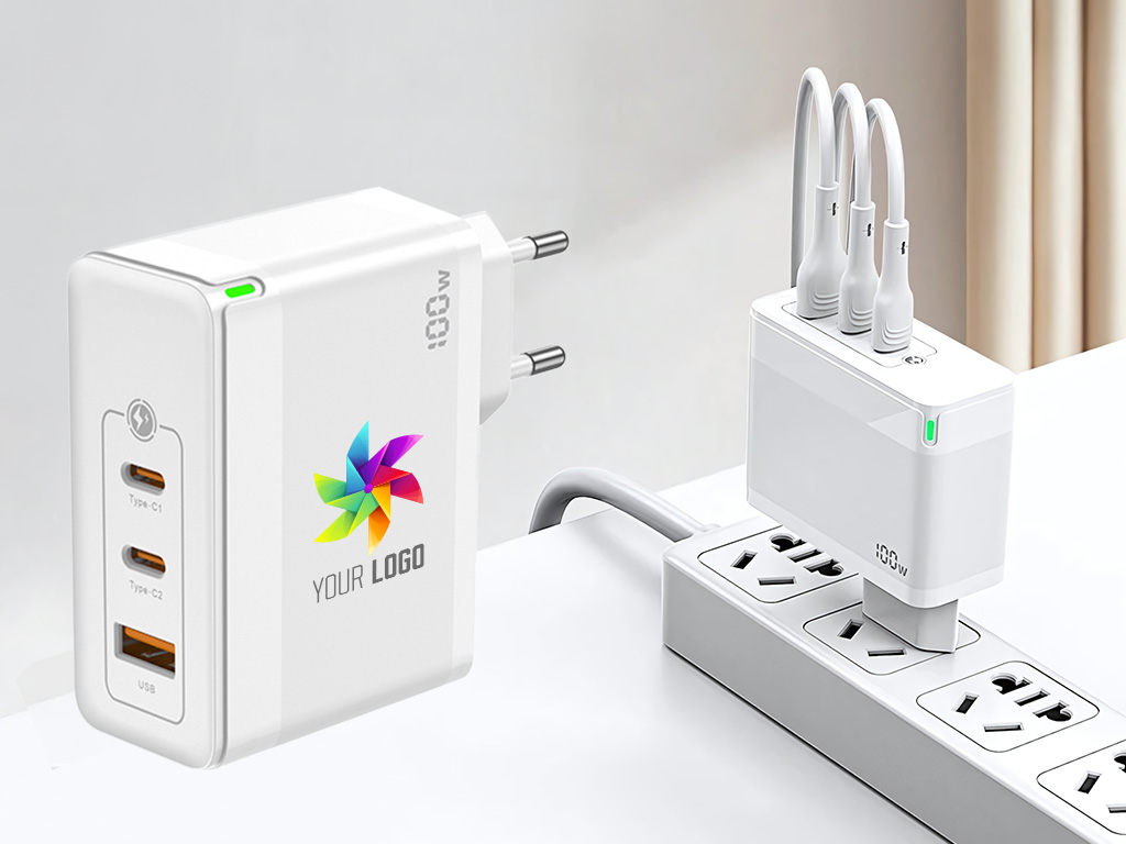 Biała ładowarka sieciowa GaN o mocy 100W z kolorowym nadrukiem logo firmy, wyposażona w dwa porty USB-C oraz jeden port USB-A do zastosowań B2B.